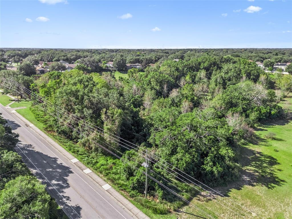 An aerial view shows a wooded lot bordered by a paved road and power lines — 2228 VICK ROAD, APOPKA, FL