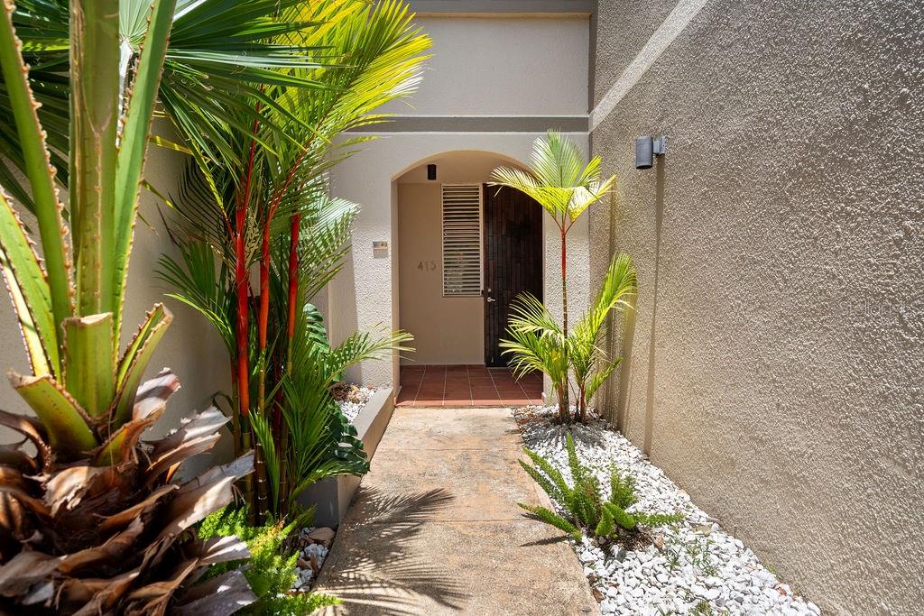 A walkway leads to the arched entrance of a building flanked by tropical plants — 693 PR UNIT 413, VEGA ALTA, PR