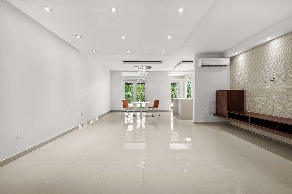A spacious, minimalist living and dining area features white tile floors, recessed lighting, and a wall-mounted media console — 693 PR UNIT 413, VEGA ALTA, PR