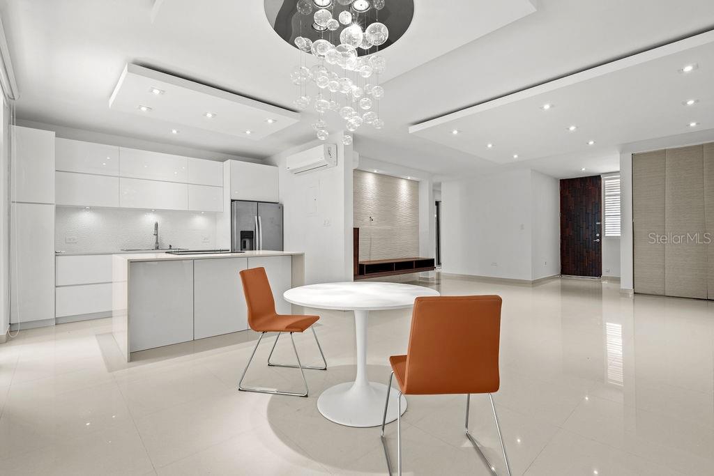 A modern open-concept kitchen and dining area features white cabinetry, glossy floors, and a chandelier — 693 PR UNIT 413, VEGA ALTA, PR