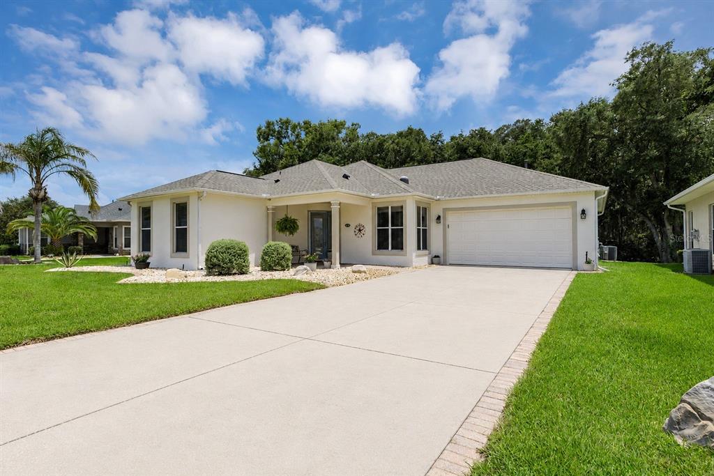 A single-story house with a beige exterior, a two-car garage, and a concrete driveway — 4436 ANTIETAM CREEK TRAIL, LEESBURG, FL
