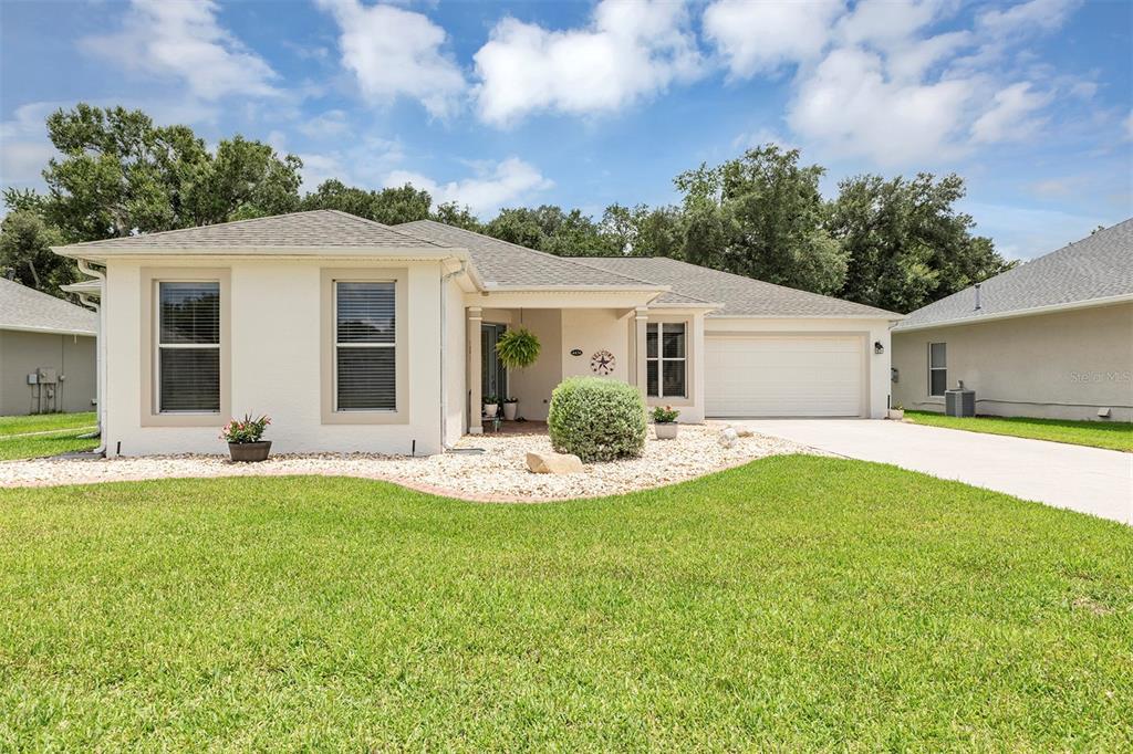 A single-story house with a white stucco exterior, a two-car garage, and a landscaped yard — 4436 ANTIETAM CREEK TRAIL, LEESBURG, FL