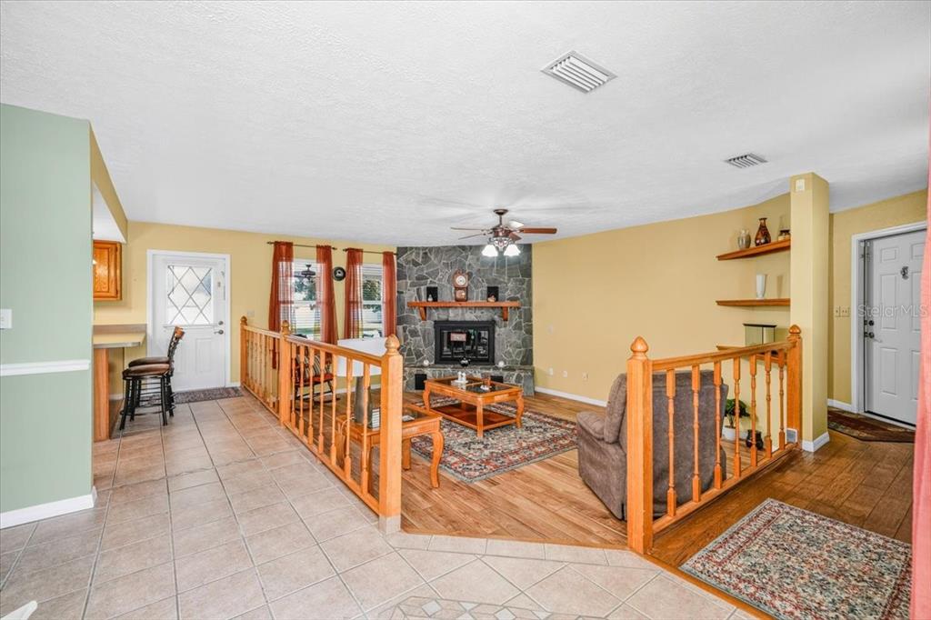 A sunken living room with a stone fireplace, wood flooring, and a wooden railing — 6483 SE 88TH STREET, OCALA, FL