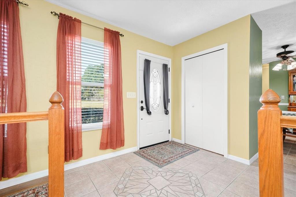 An entryway features a white front door, a closet, tile flooring, and yellow walls — 6483 SE 88TH STREET, OCALA, FL