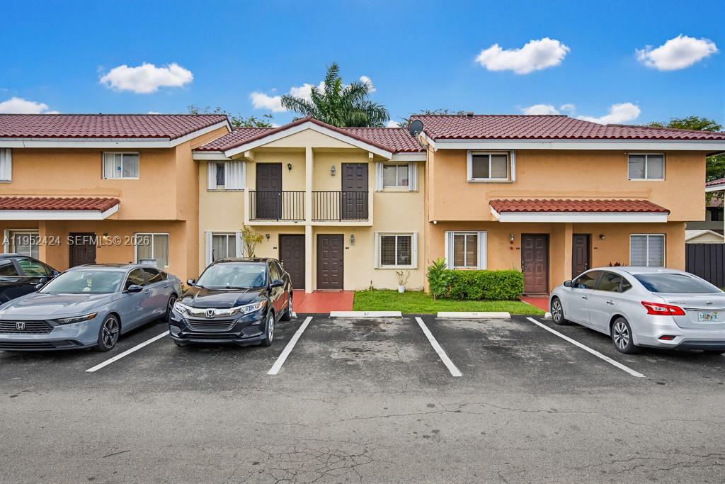 A two-story residential building with tan stucco walls and a red tile roof — 560 NW 82nd Pl # 306, Miami FL 33126, MIAMI, FL