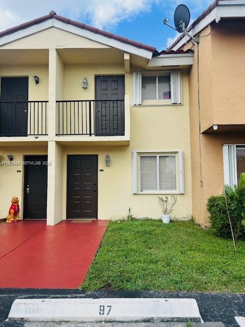 A two-story townhouse exterior features a red walkway, a small lawn, and a parking space — 560 NW 82nd Pl # 306, Miami FL 33126, MIAMI, FL