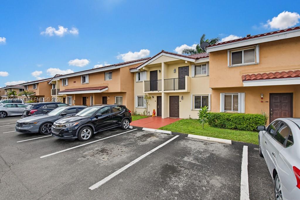 An exterior view of a two-story apartment building with a parking lot in front — 560 NW 82nd Pl # 306, Miami FL 33126, MIAMI, FL