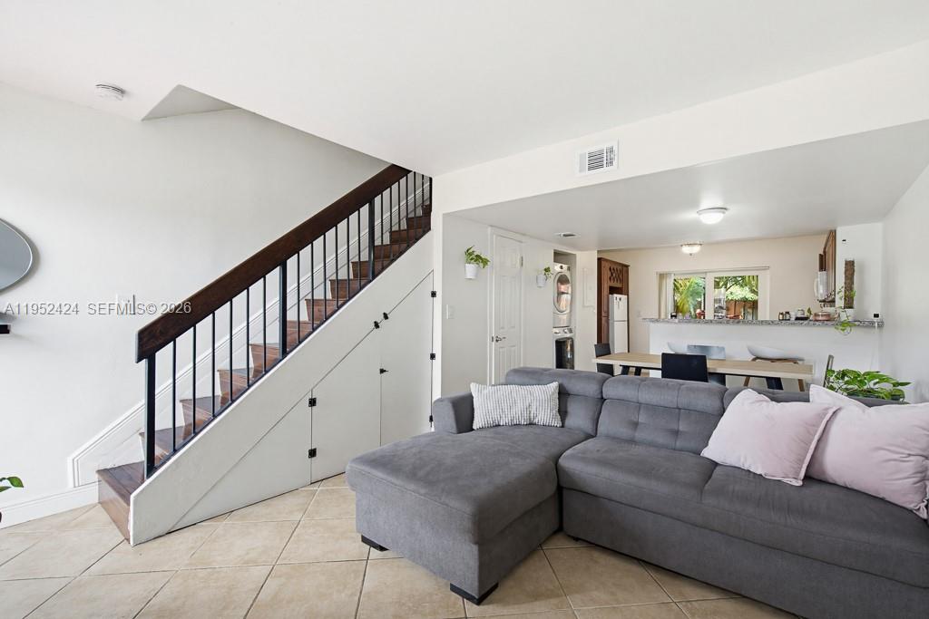 A living room features a grey sectional sofa, tiled floors, and a staircase with storage — 560 NW 82nd Pl # 306, Miami FL 33126, MIAMI, FL