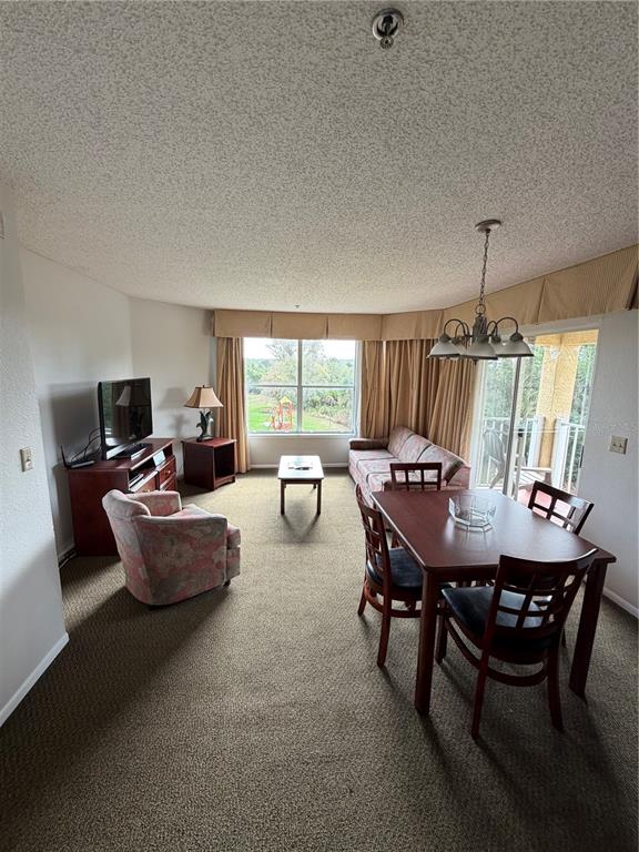 A carpeted living and dining area features a television, sofa, and sliding glass balcony doors — 6336 PARC CORNICHE DRIVE UNIT 3307, ORLANDO, FL