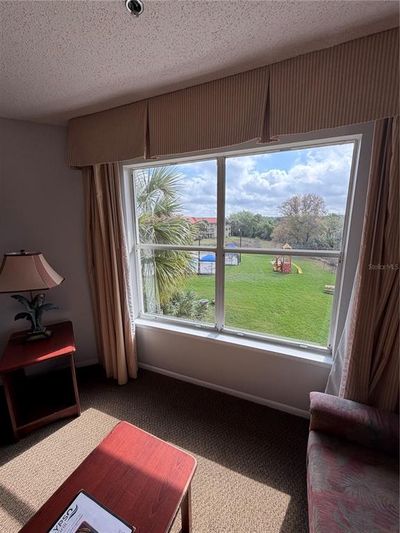 A room with a large window overlooking a grassy area, playground, and swimming pool — 6336 PARC CORNICHE DRIVE UNIT 3307, ORLANDO, FL