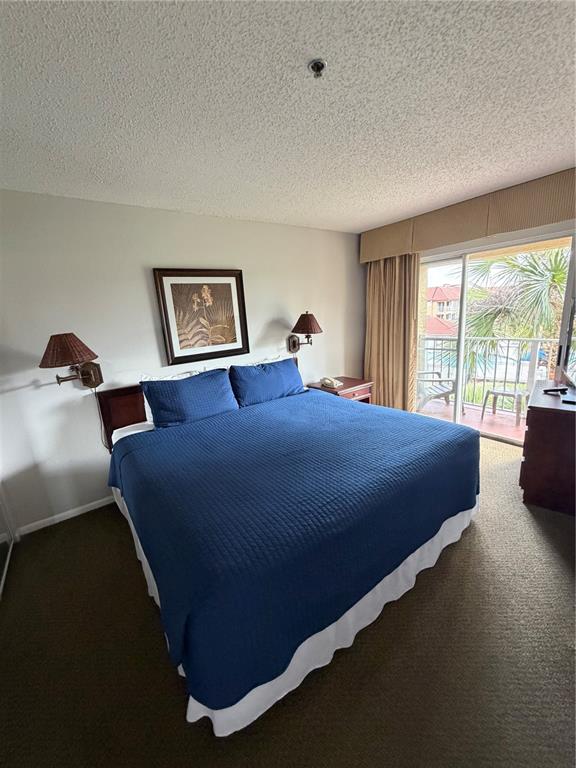 A bedroom features a king bed with a blue quilt, two wall lamps, and a balcony — 6336 PARC CORNICHE DRIVE UNIT 3307, ORLANDO, FL