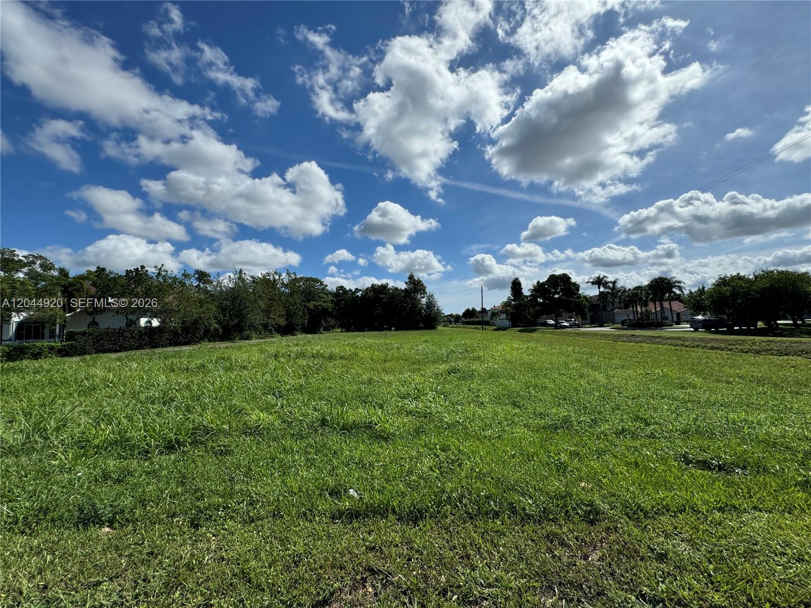 A large, grassy vacant lot under a bright blue sky with scattered clouds — 3494 S Jog Rd, Green Acres FL 33467, GREEN ACRES, FL