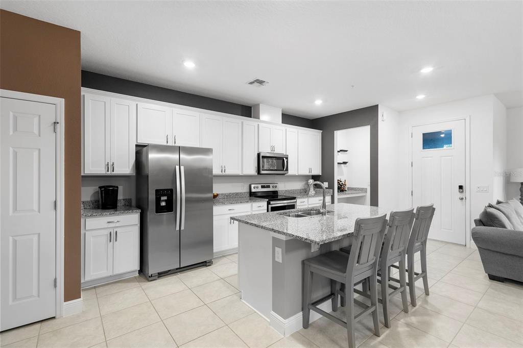 A kitchen with white cabinets, granite countertops, stainless steel appliances, and a central island — 14989 APOLLO BOND DRIVE, WINTER GARDEN, FL