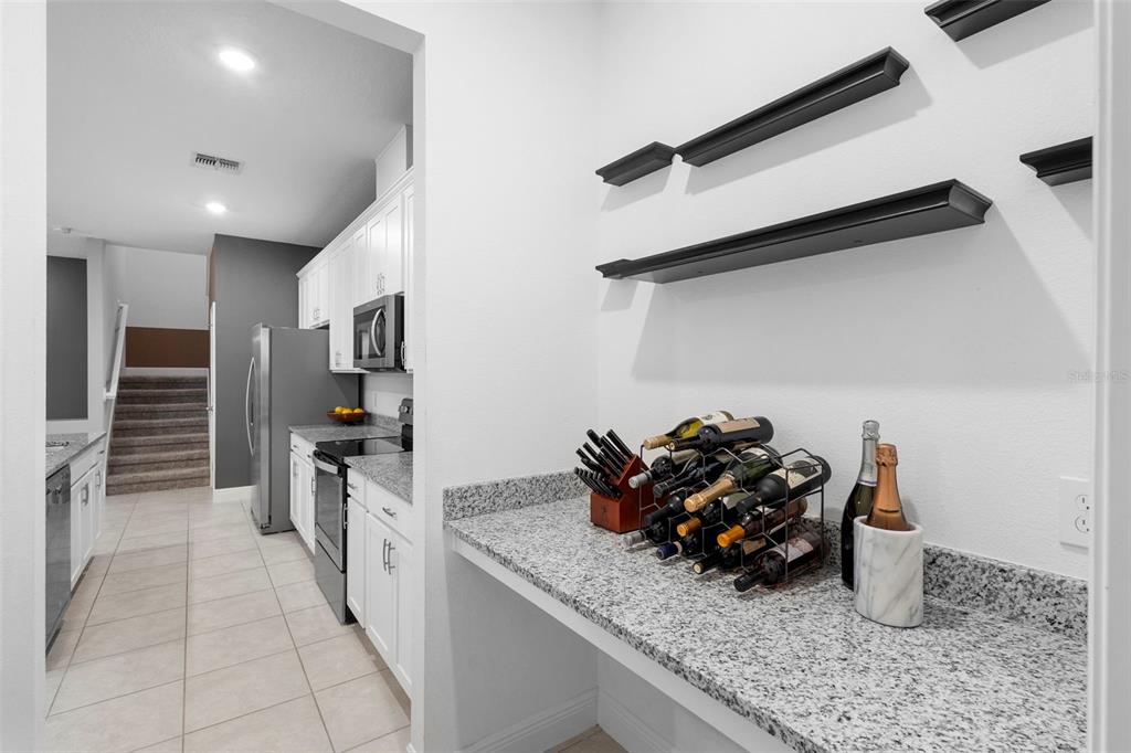 A kitchen area features granite countertops, white cabinets, a wine rack, and floating shelves — 14989 APOLLO BOND DRIVE, WINTER GARDEN, FL