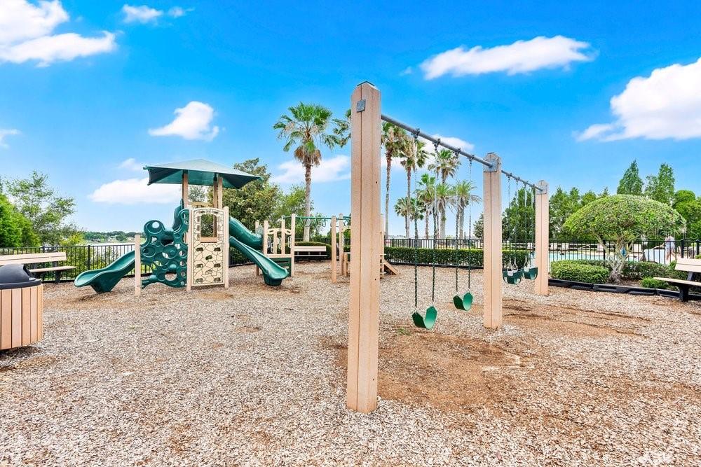 A playground with a swing set and a climbing structure sits on wood chips — 4265 JULIANA LAKE DRIVE, AUBURNDALE, FL