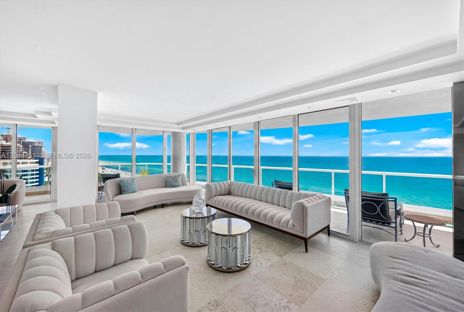 A modern living room features light-colored furniture, mirrored coffee tables, and floor-to-ceiling windows overlooking the ocean — 5025 Collins Ave # 1105, Miami Beach FL 33140, MIAMI BEACH, FL