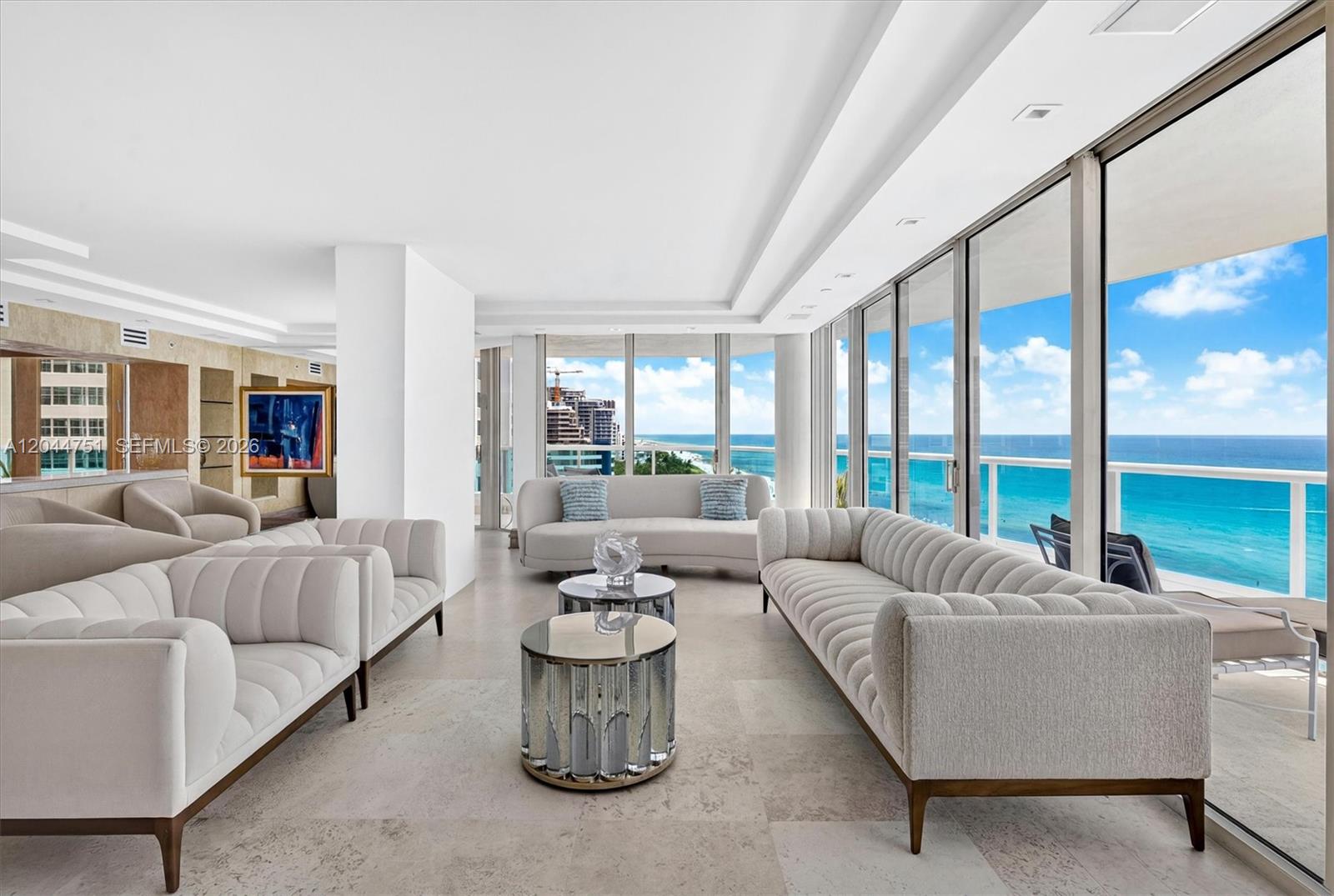 A bright living room features white tufted sofas, mirrored coffee tables, and floor-to-ceiling ocean views — 5025 Collins Ave # 1105, Miami Beach FL 33140, MIAMI BEACH, FL