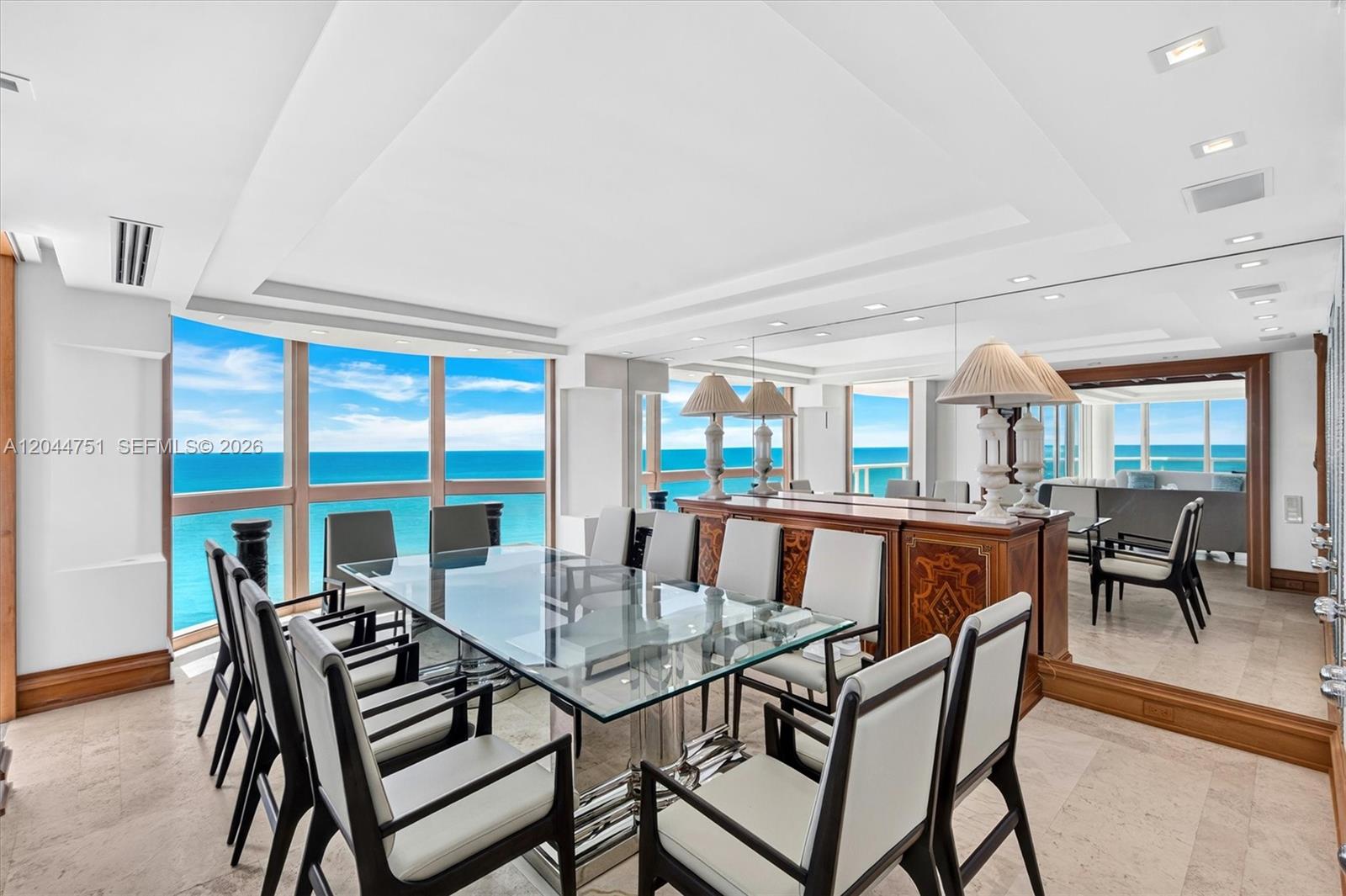 A dining room with a glass table, modern chairs, and floor-to-ceiling windows overlooking the ocean — 5025 Collins Ave # 1105, Miami Beach FL 33140, MIAMI BEACH, FL