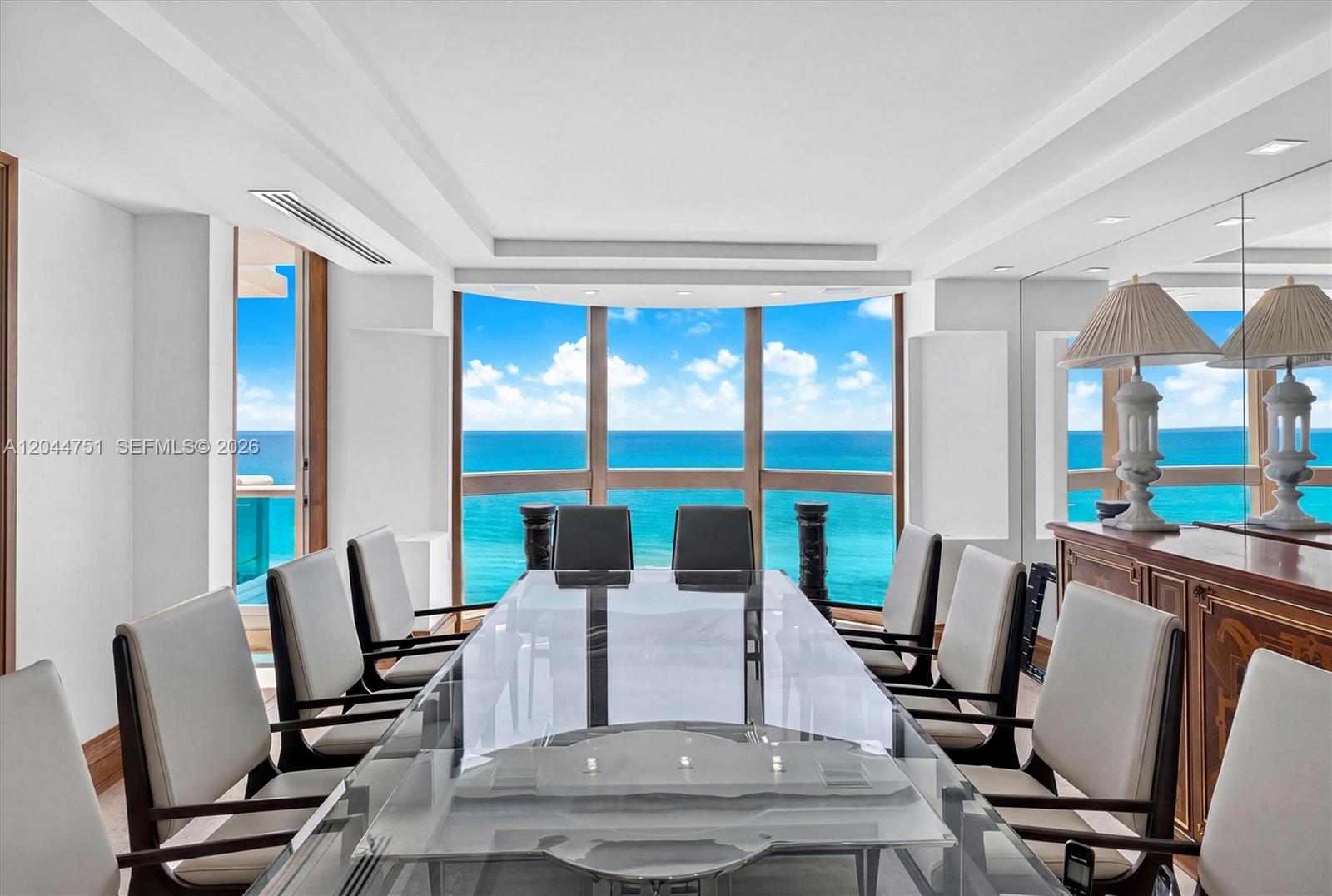 A dining room features a glass table, ten chairs, and floor-to-ceiling windows overlooking the ocean — 5025 Collins Ave # 1105, Miami Beach FL 33140, MIAMI BEACH, FL