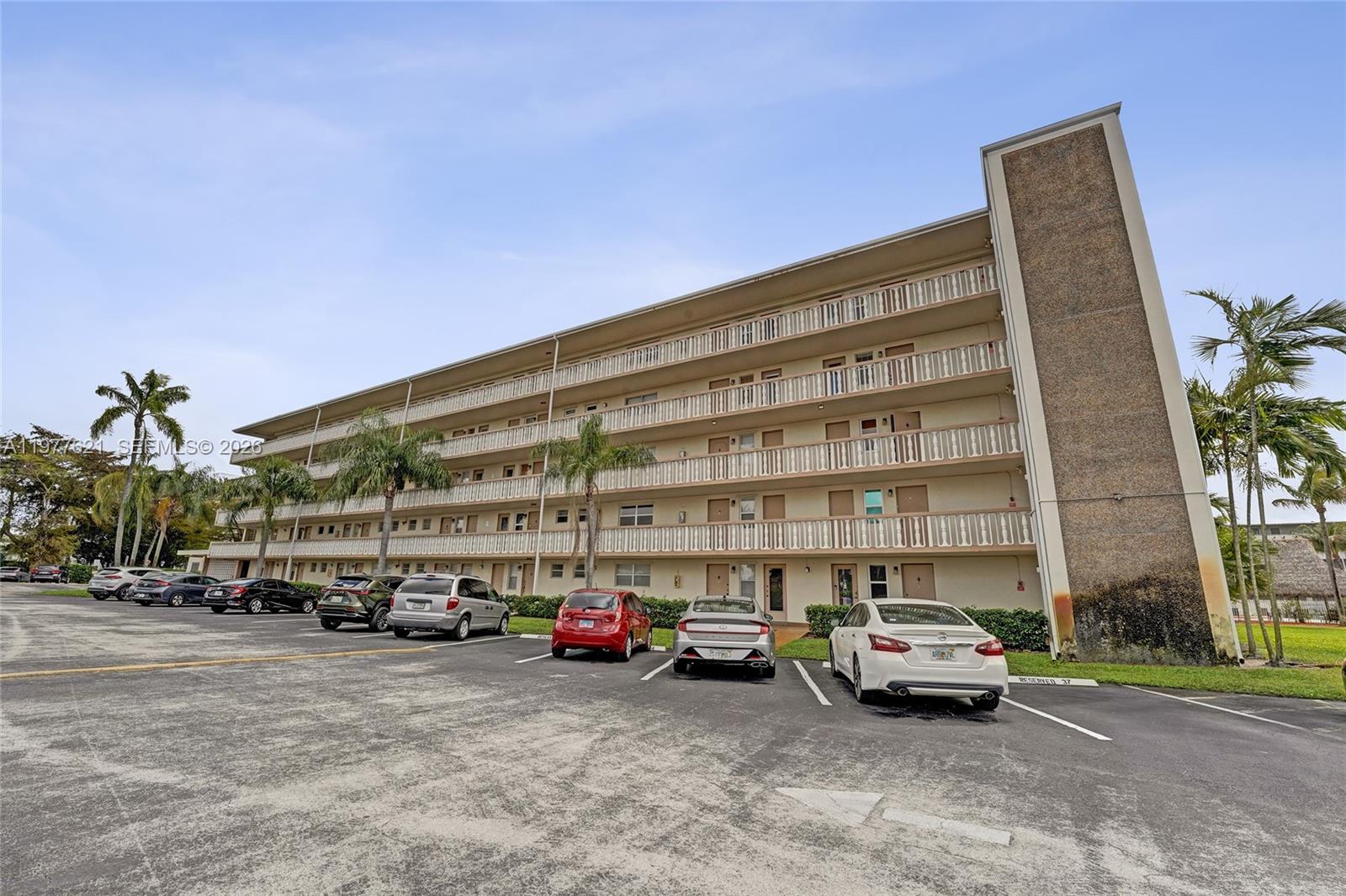 A multi-story apartment building with exterior balconies and a parking lot in front — 4650 Washington St # 209, Hollywood FL 33021, HOLLYWOOD, FL