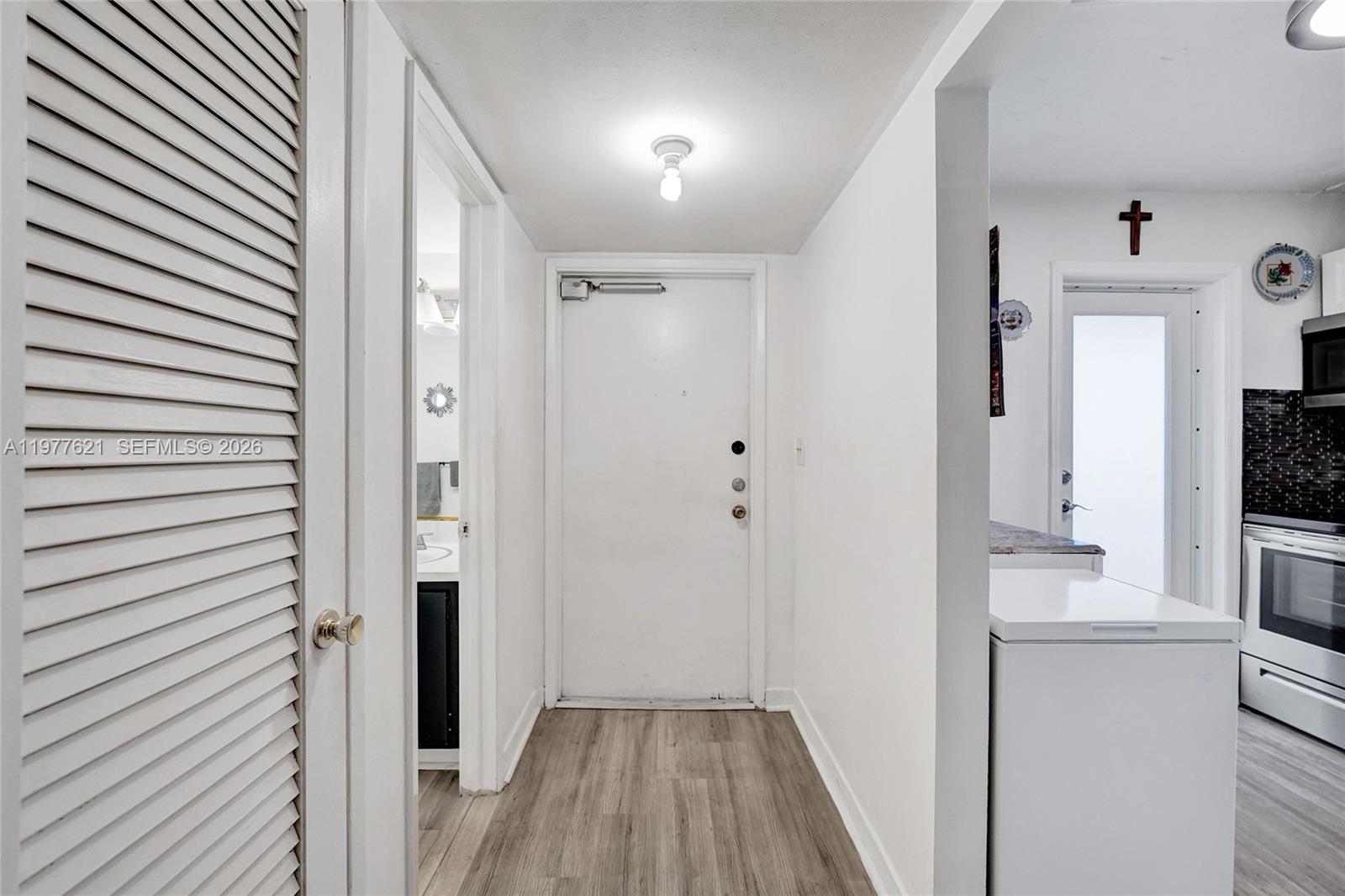 A hallway leads to an entrance door, with a bathroom on the left and kitchen — 4650 Washington St # 209, Hollywood FL 33021, HOLLYWOOD, FL