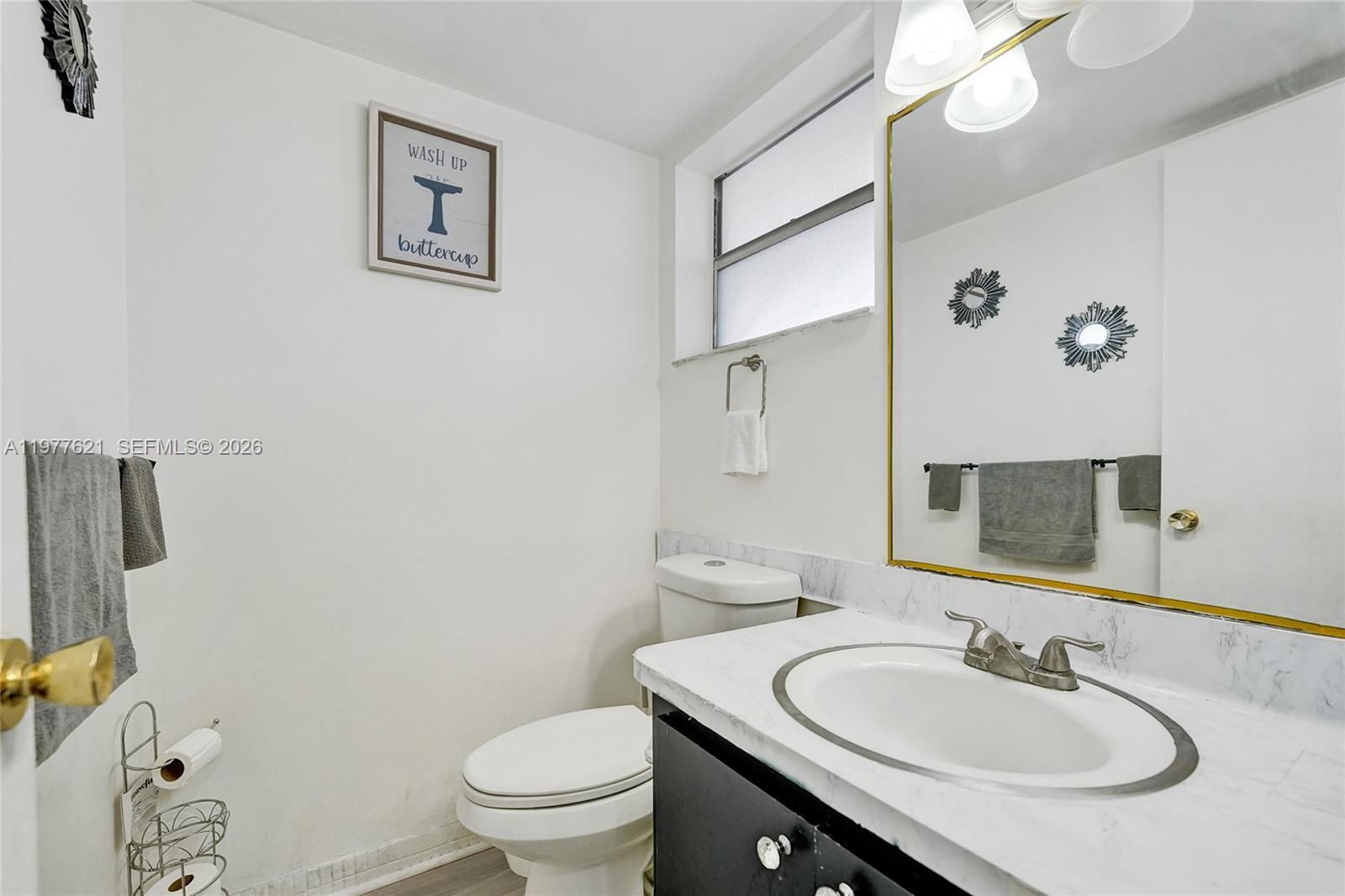 A bathroom features a white toilet, a vanity with a marble-look countertop, and a mirror — 4650 Washington St # 209, Hollywood FL 33021, HOLLYWOOD, FL