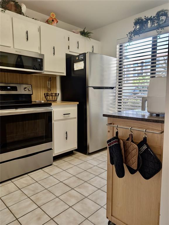 A kitchen features white cabinets, stainless steel appliances, a tiled floor, and a rolling island — 6218 PALMA DEL MAR BOULEVARD S UNIT 114, ST PETERSBURG, FL