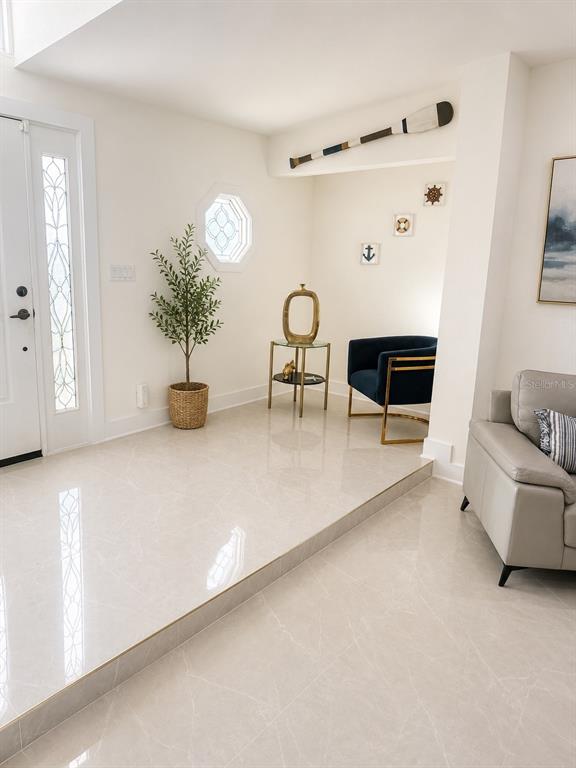 A bright entryway features light tile floors, a step-up transition, and a navy accent chair — 452 BATH CLUB BOULEVARD N, NORTH REDINGTON BEACH, FL