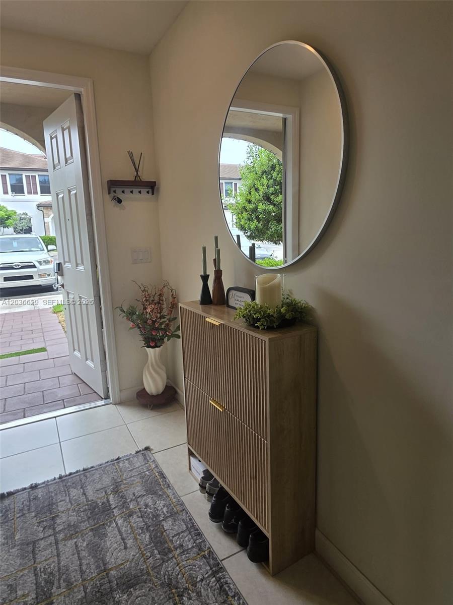 An entryway features a wood-slatted shoe cabinet, a round mirror, and a door opening outdoors — 10963 W 32nd Ln, Hialeah FL 33018, HIALEAH, FL