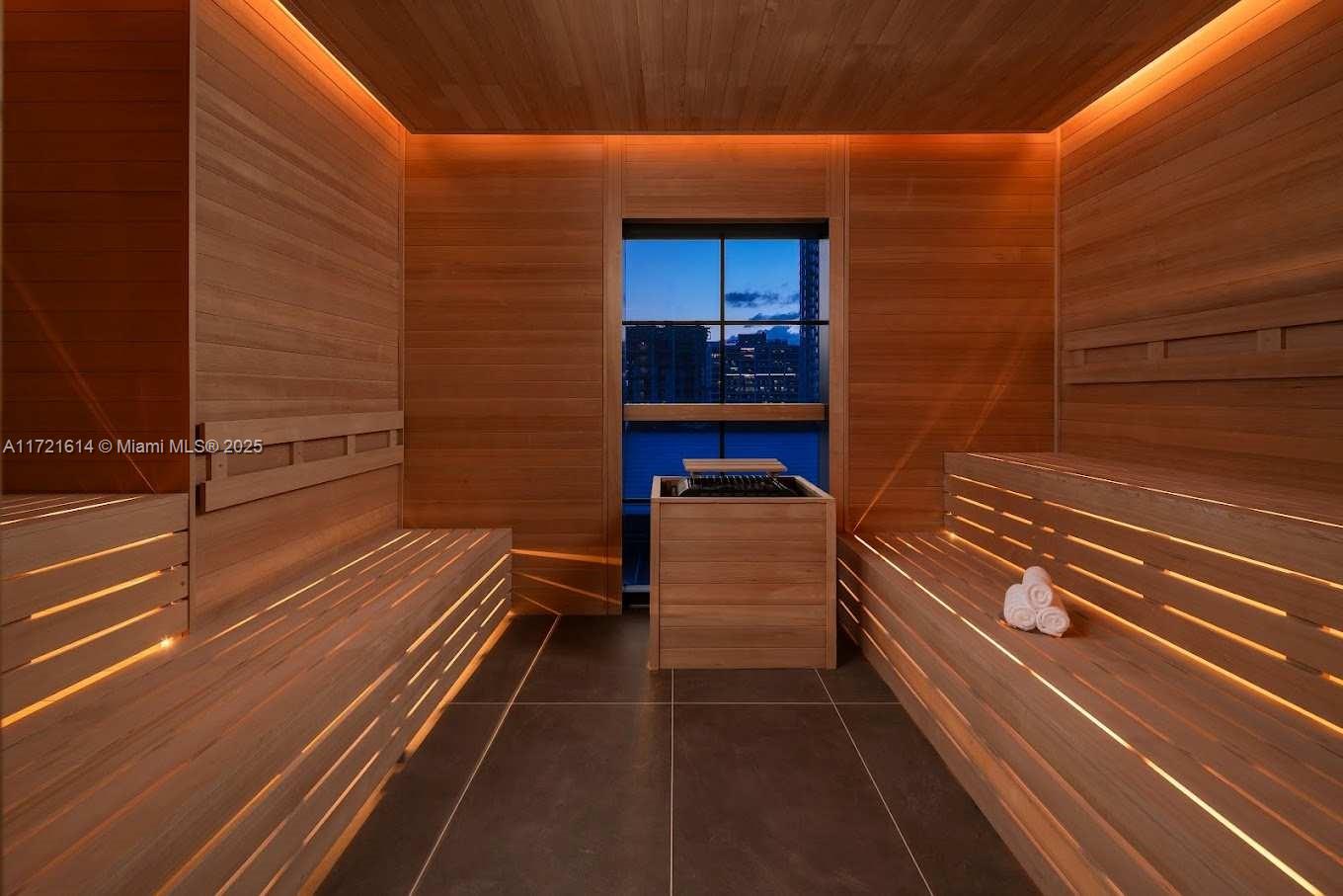 A modern cedar sauna features tiered wooden benches, integrated lighting, and a window overlooking cityscapes — 159 NE 6 # 3912, Miami FL 33132, MIAMI, FL