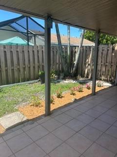 A covered patio overlooks a small backyard with a wooden fence and a garden bed — 18970 Cloud Lake Circle, Boca Raton FL 33496, BOCA RATON, FL