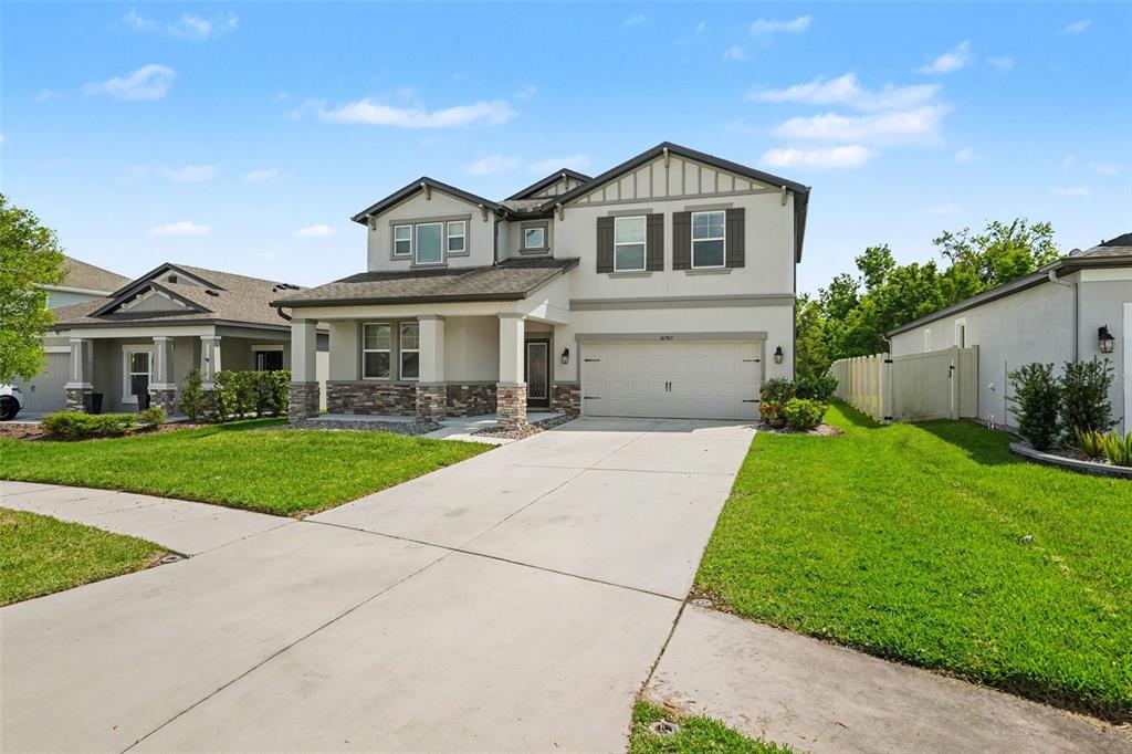A two-story suburban house with a stone-accented porch, a two-car garage, and a concrete driveway — 30789 PARROT REEF COURT, WESLEY CHAPEL, FL