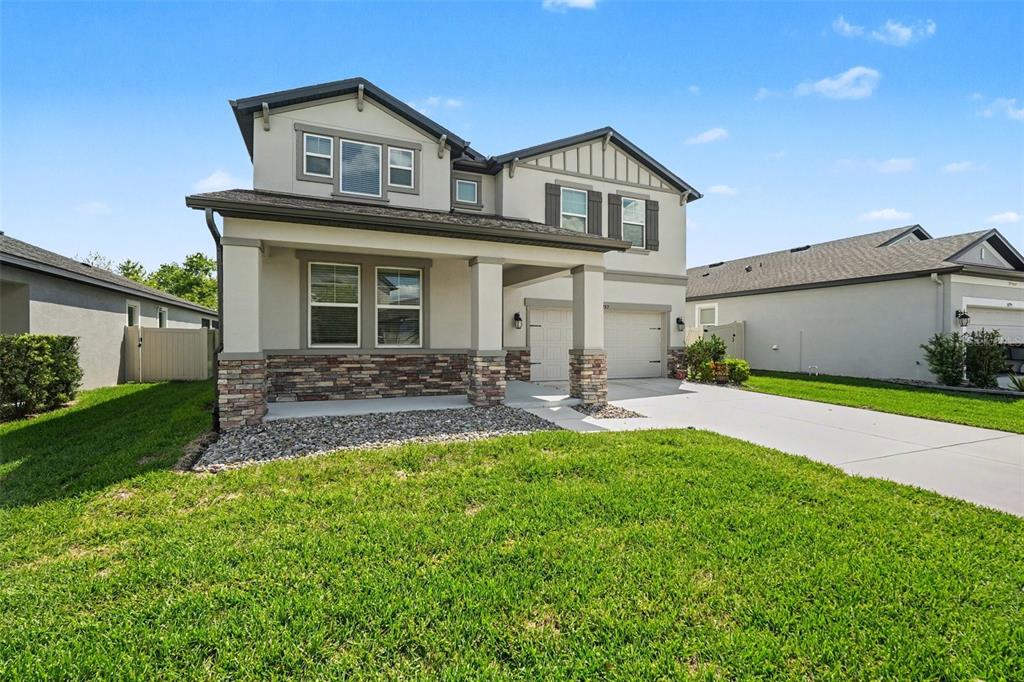 A two-story suburban house with a stone-veneer base, covered front porch, and attached garage — 30789 PARROT REEF COURT, WESLEY CHAPEL, FL
