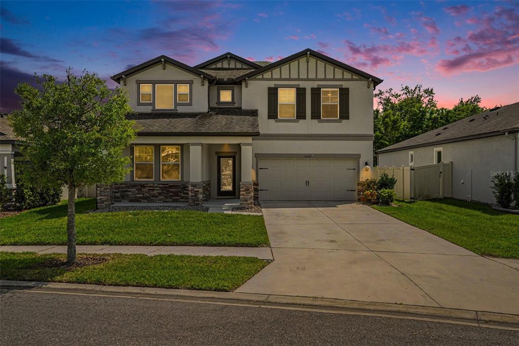 A two-story suburban house features a stone-accented facade, a two-car garage, and a concrete driveway — 30789 PARROT REEF COURT, WESLEY CHAPEL, FL