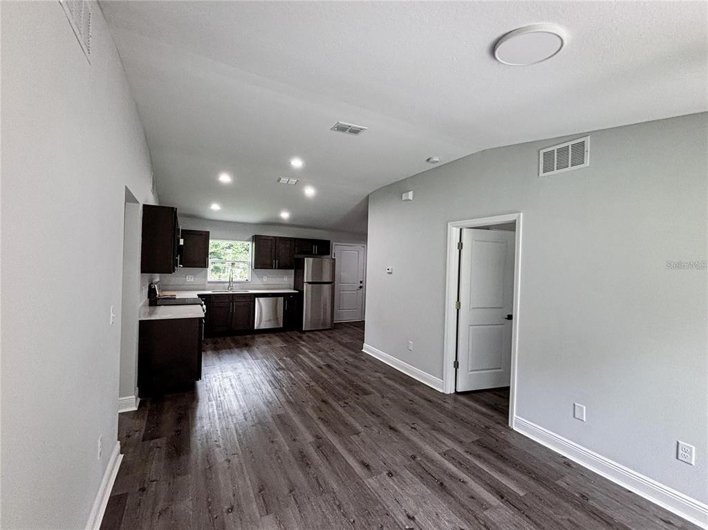 A kitchen with dark cabinets and stainless steel appliances opens into a living area — 31 REDWOOD TRACK RUN, OCALA, FL