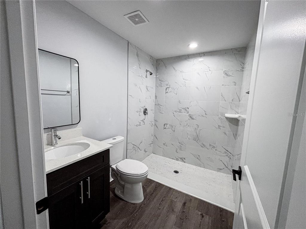 A bathroom features a dark wood vanity, a white toilet, and a tiled walk-in shower — 31 REDWOOD TRACK RUN, OCALA, FL