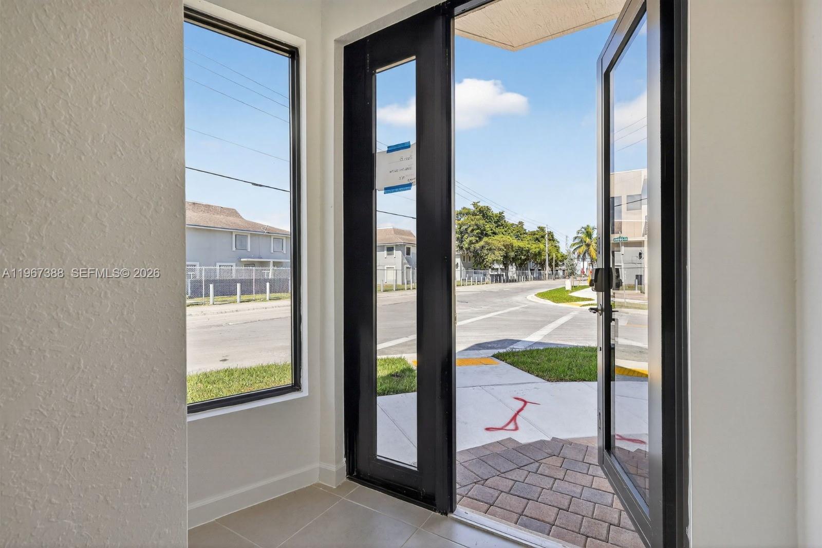 An open front door reveals a view of a suburban street and sidewalk — 13888 SW 261st Ter # 0, Miami FL 33032, MIAMI, FL
