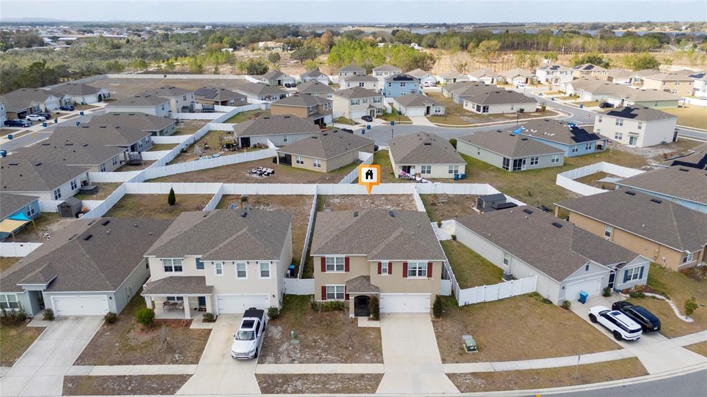 An aerial view shows a suburban neighborhood with two-story houses and white vinyl privacy fences — 740 SQUIRES GROVE DRIVE, WINTER HAVEN, FL