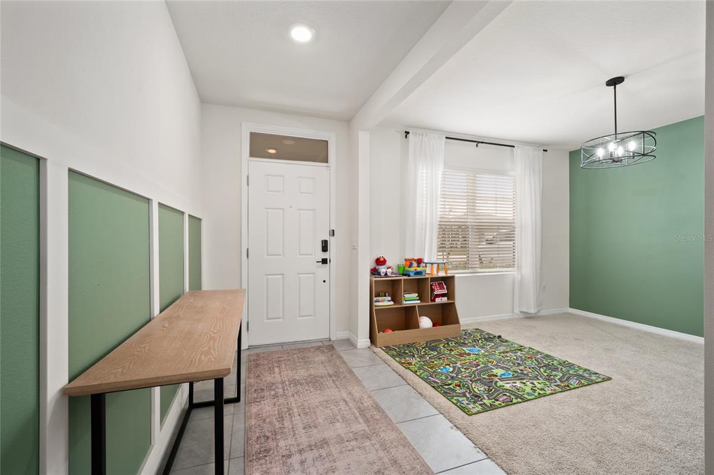 A room with a front door, a wooden desk, a toy shelf, and green accent walls — 740 SQUIRES GROVE DRIVE, WINTER HAVEN, FL