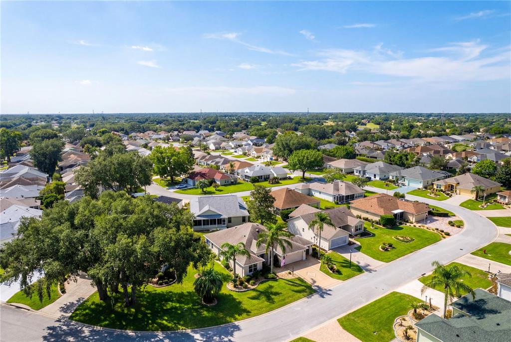 An aerial view shows a suburban neighborhood with single-family homes, paved streets, and mature trees — 16905 SE 93RD CUTHBERT CIRCLE, THE VILLAGES, FL