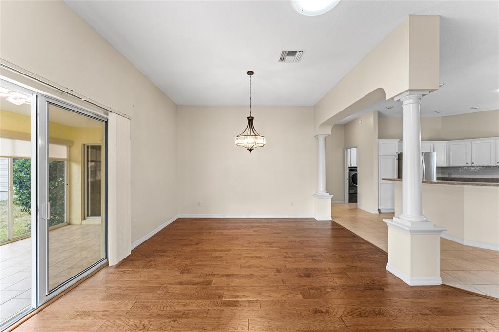 An empty dining room with hardwood floors, a hanging light fixture, and sliding glass doors — 16905 SE 93RD CUTHBERT CIRCLE, THE VILLAGES, FL