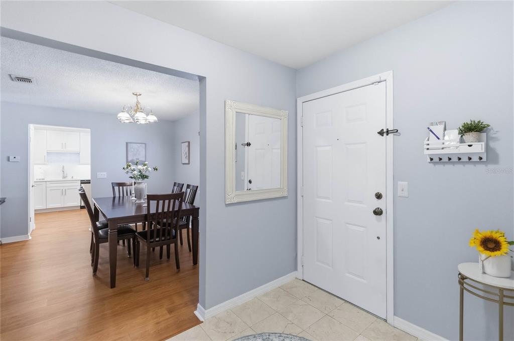 An entryway with light blue walls and tile flooring leads into a dining room — 6206 BAYHILL LANE UNIT 6206, LONGWOOD, FL