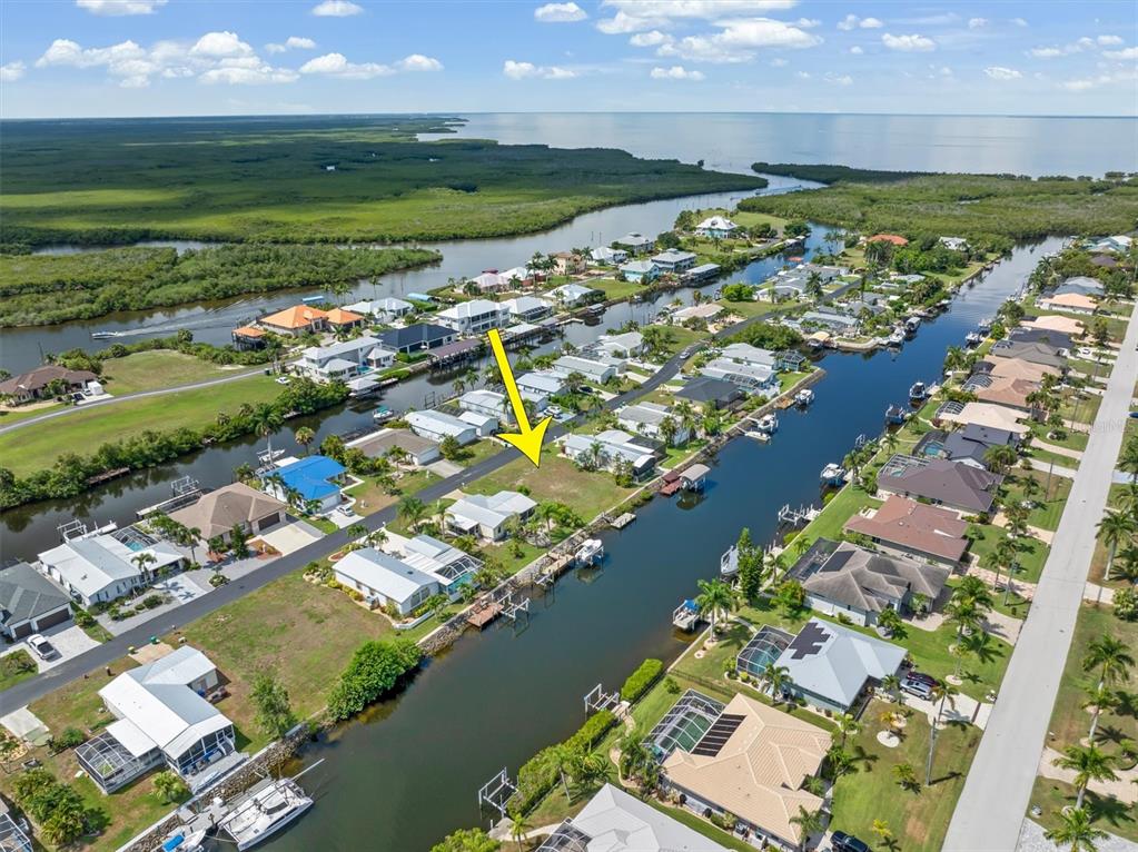 An aerial view shows a vacant waterfront lot marked by a yellow arrow — 5439 RIVER BAY DRIVE, PUNTA GORDA, FL