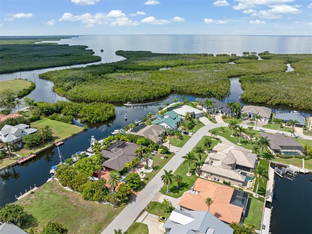 An aerial view shows waterfront houses with docks and pools along a canal near mangroves — 5439 RIVER BAY DRIVE, PUNTA GORDA, FL