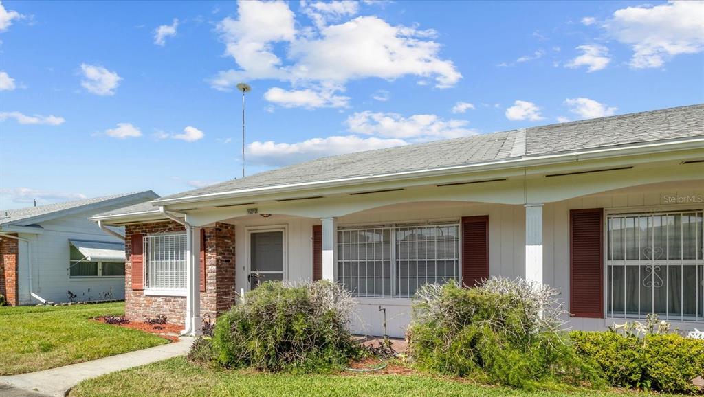 A single-story house exterior features a covered porch, brick accents, and white siding — 1213 8TH STREET NW, WINTER HAVEN, FL