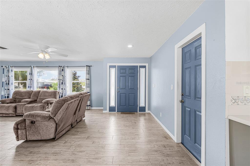 A living room features light blue walls, wood-look tile flooring, and two blue doors — 1320 SE 26TH TERRACE, CAPE CORAL, FL