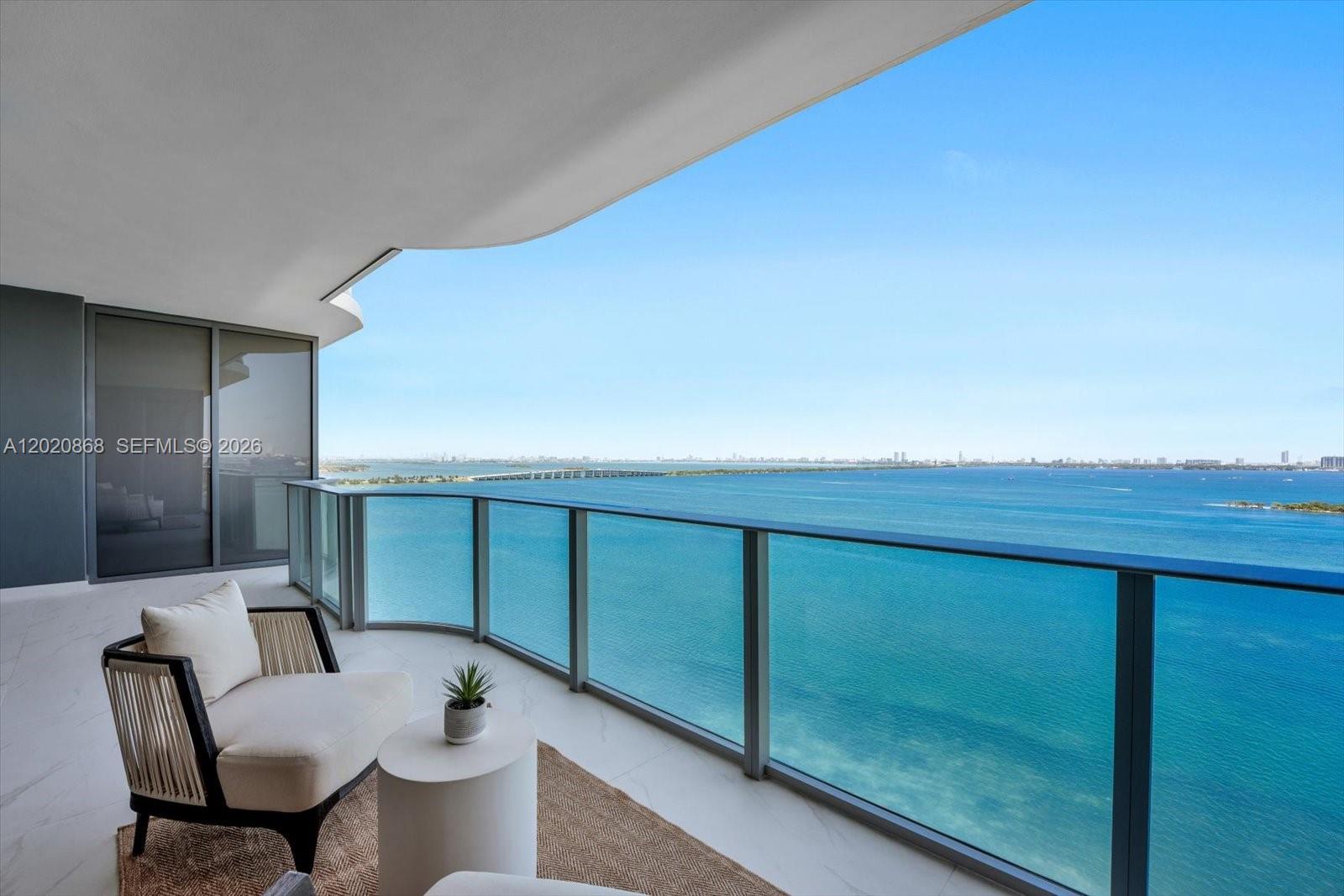 A balcony with a glass railing overlooks a wide expanse of blue water — 700 NE 24th St # 1602, Miami FL 33137, MIAMI, FL