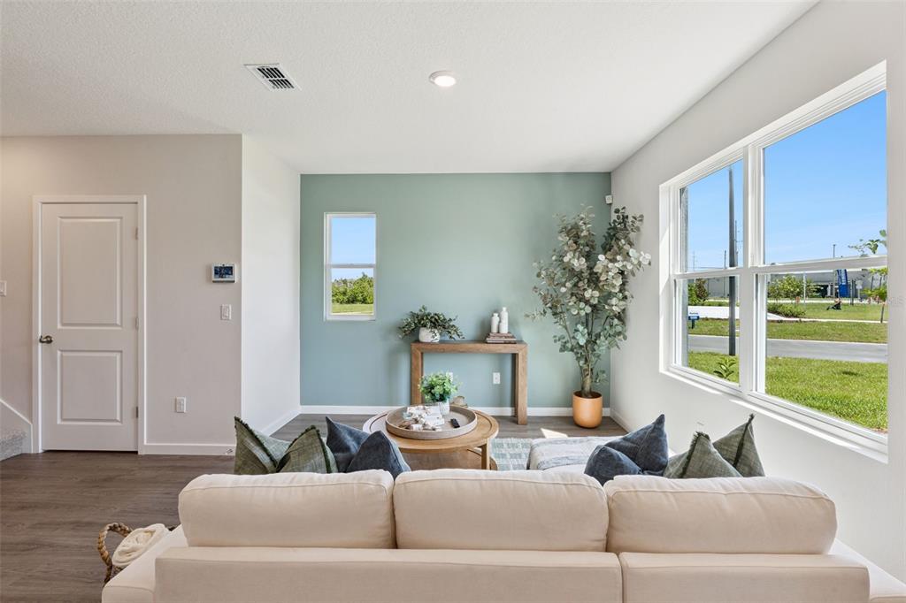 A living room features a light blue accent wall, a beige sofa, and large windows — 2253 RITA LANE, KISSIMMEE, FL