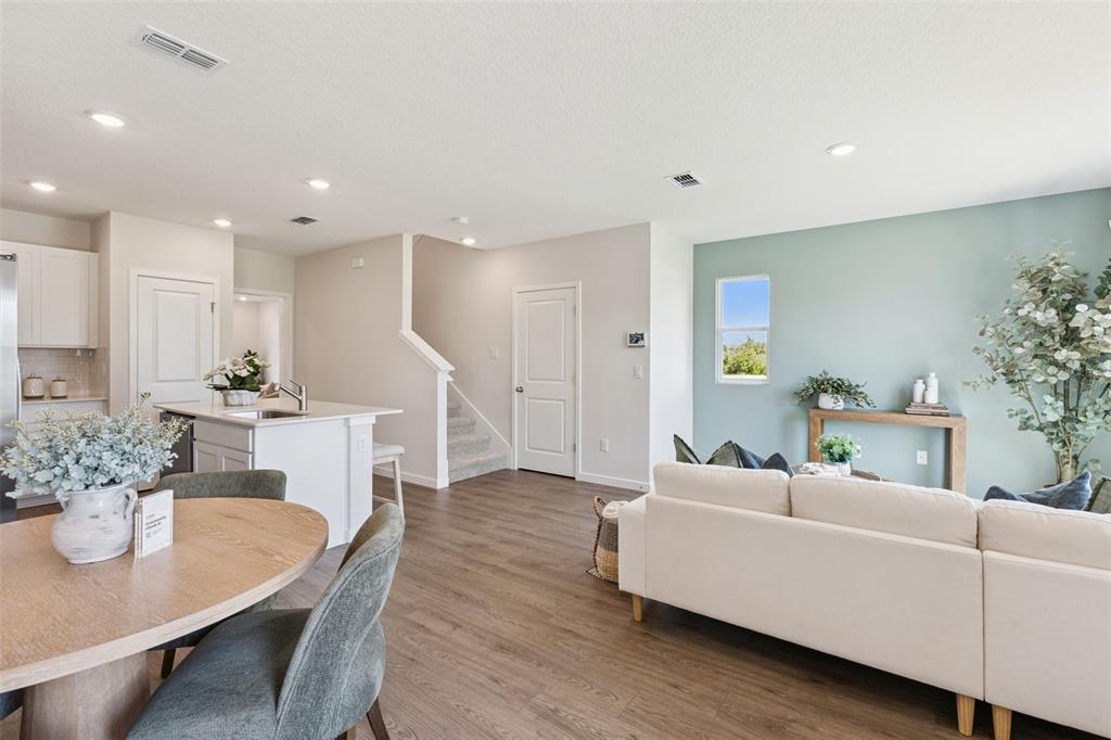 An open-concept living and dining area features wood-look flooring, a kitchen island, and blue walls — 2253 RITA LANE, KISSIMMEE, FL