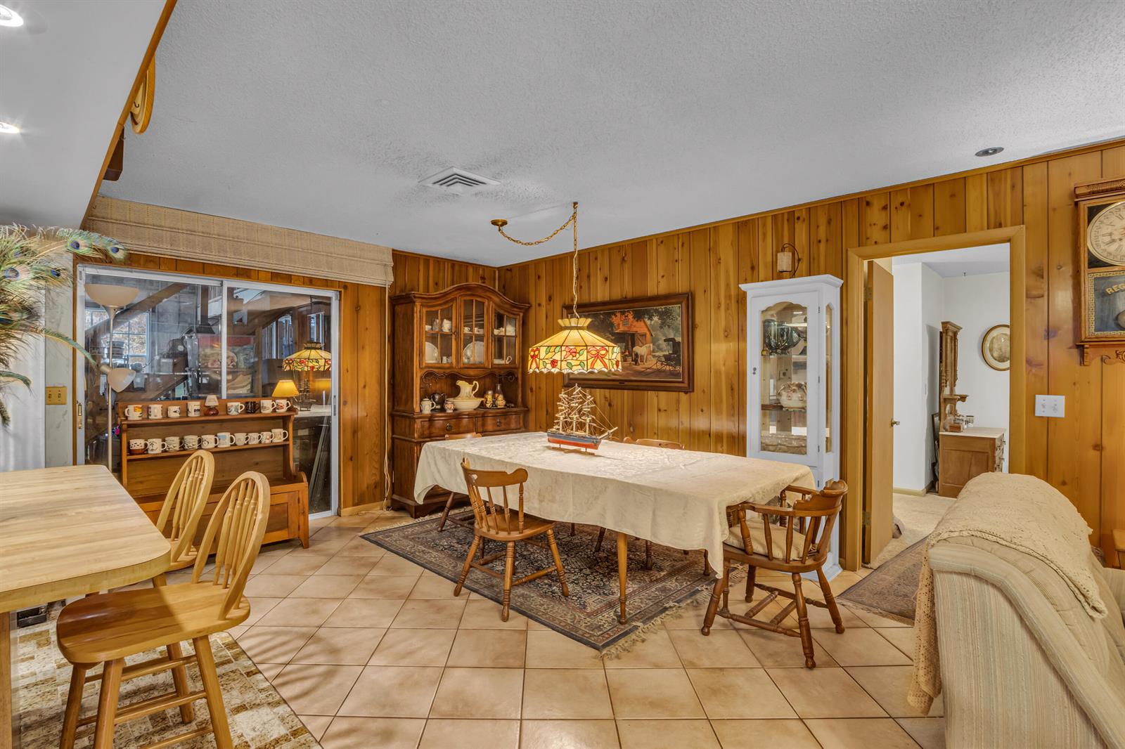 A dining room features wood-paneled walls, tile flooring, a hutch, and a central pendant light — 14181 35th Place N, FL 33470, FL